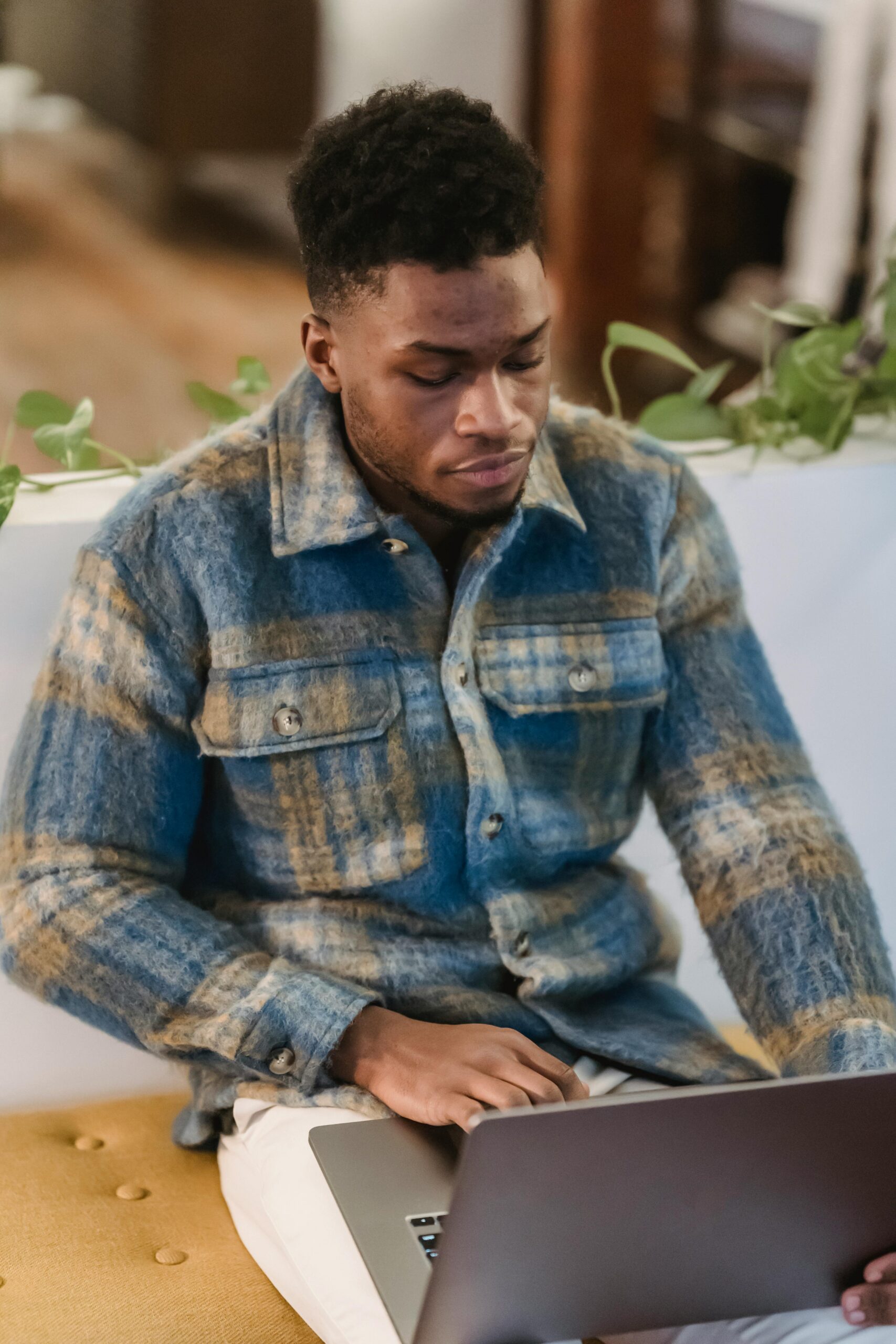 Young man in a casual setting intensely focused on his laptop, indoors.